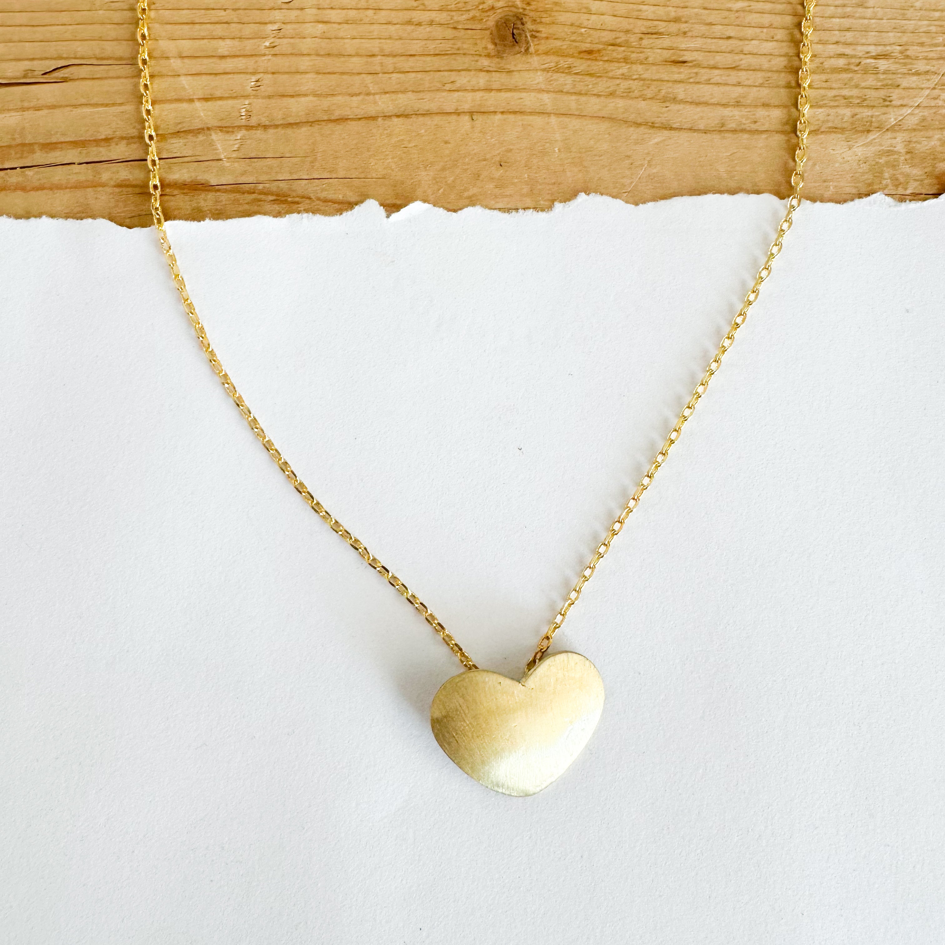 Gold toned necklace featuring a solid gold toned heart.