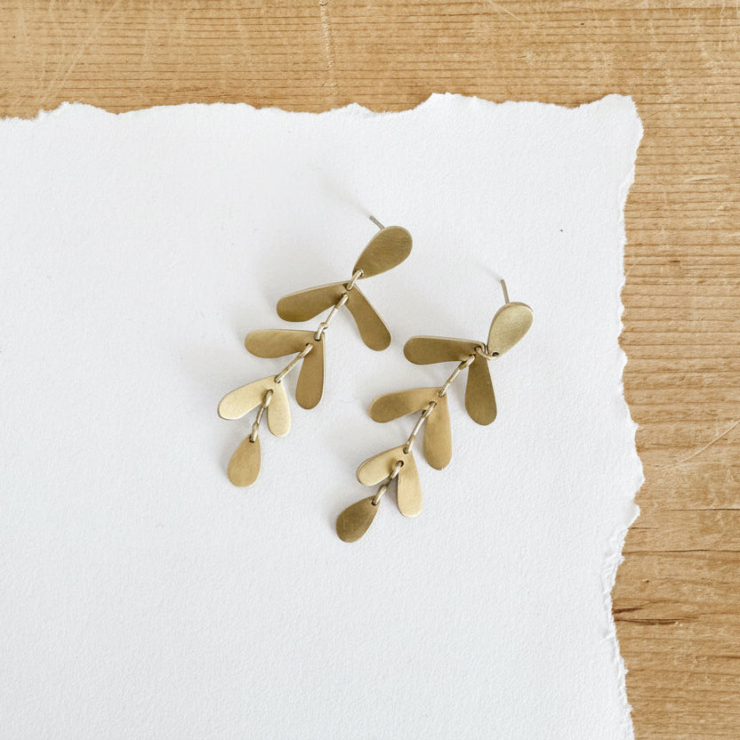 Gold toned earrings featuring three sets of leaves dropping from post.