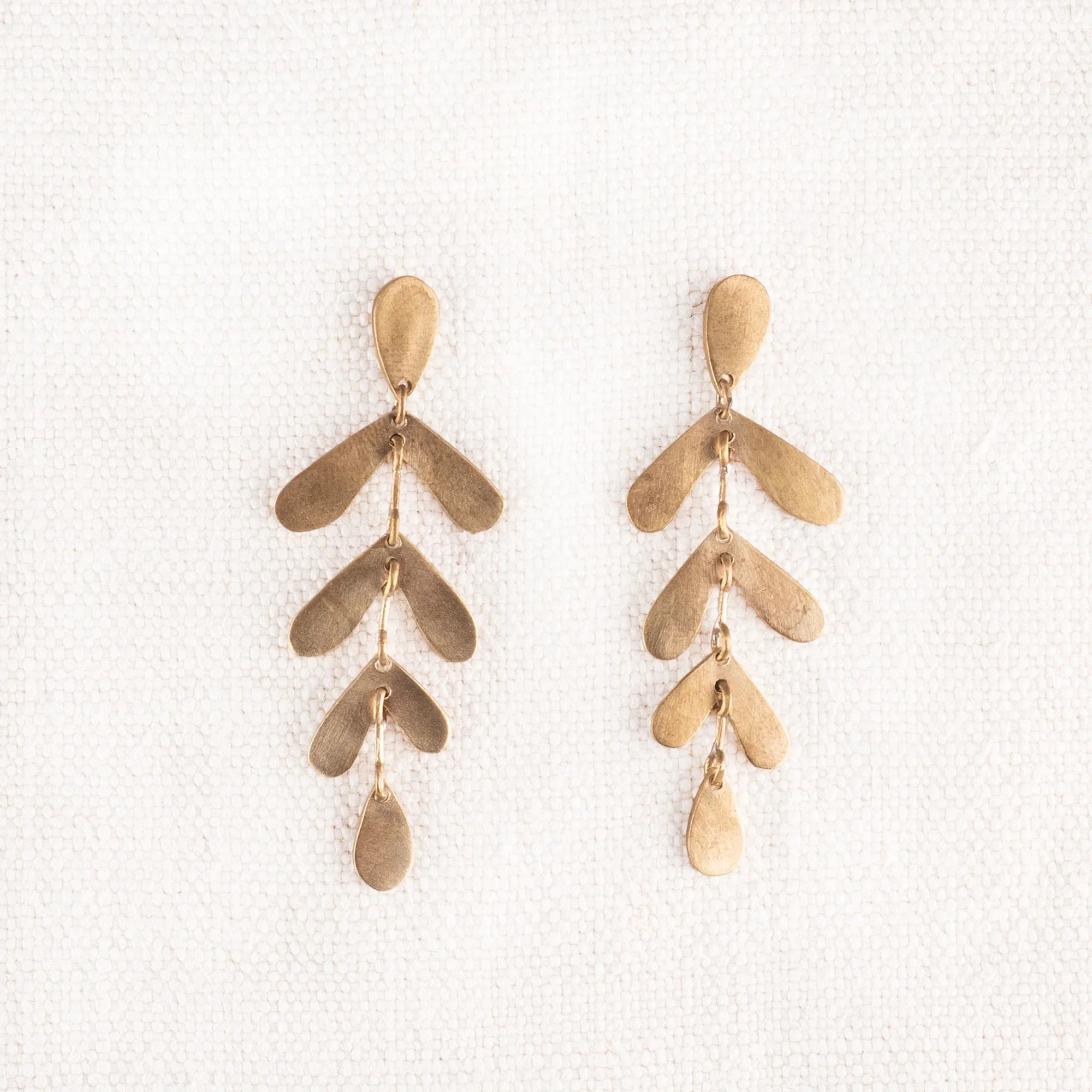 Gold toned earrings featuring three sets of leaves dropping from post.
