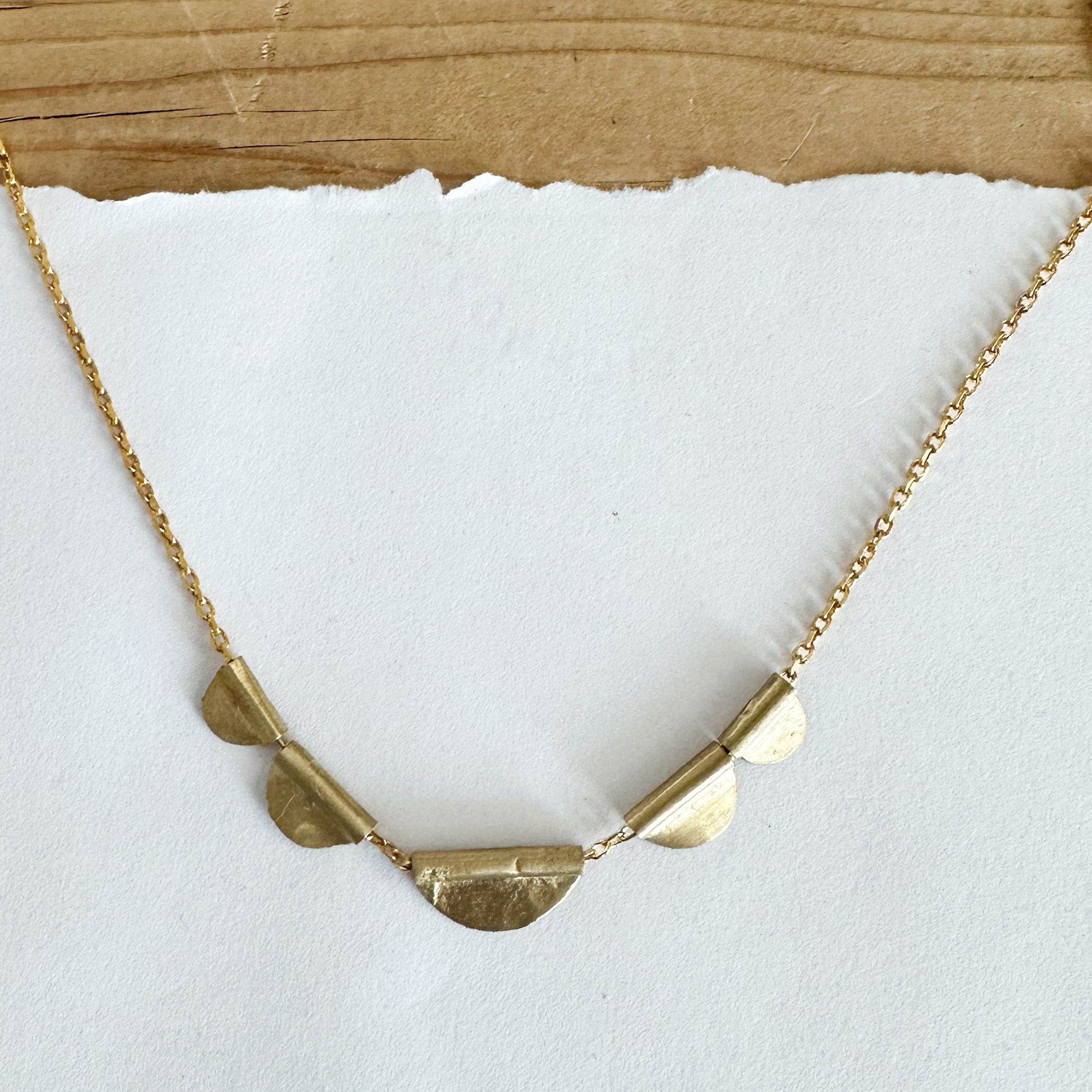 Gold tone necklace featuring gold tone semi circular tabs.
